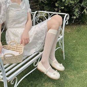Close-up of white lace mesh knee-high socks with delicate floral hollow patterns