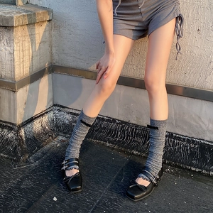 Detail of grey knitted leg warmers with black bow and Mary Jane shoes in sunlight