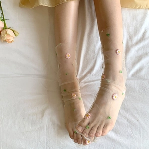 Macro detail of delicate daisy embroidery on sheer ultra-thin breathable mesh socks