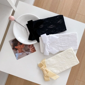 Drei Paar Spitzenkniestrümpfe in Schwarz, Weiß und Beige mit Samtschleifen auf dem Tisch