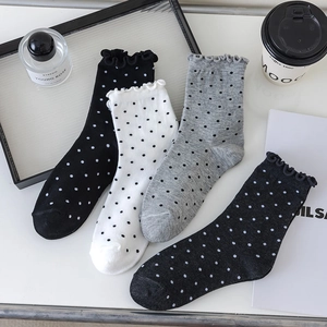 Detailed view of four pairs of polka dot crew socks with frill cuffs in a flat lay setup