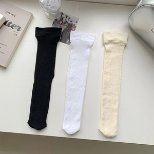 Detail of three-pack hollow mesh knee-high socks in black white and beige knit