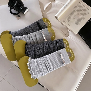 Close-up of knit leg warmers with silver bow details and ruffled edges on premium packaging