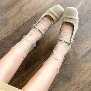 Close-up of white mesh socks with daisy embroidery and beige Mary Jane shoes