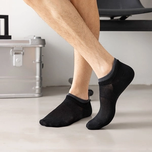 Close-up of black breathable mesh ankle socks with grey ribbed edges on men's feet