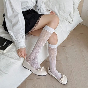 Detail of white lace hollow-out knee high socks with delicate floral patterns