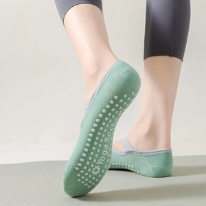 Macro detail of green yoga socks with grey cross straps and anti-slip silicone dots