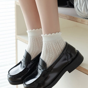 Close-up of white lace socks with hollow pattern paired with black patent leather loafers