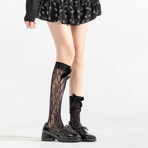 Detail von schwarzen floralen Spitzen-Socken mit Samtschleife und Mary Jane Schuhen