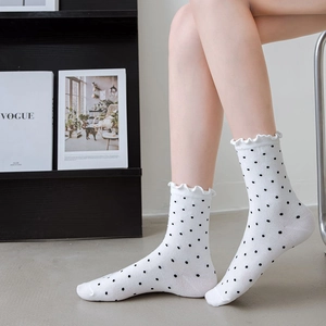 Detail of white cotton mid-calf socks with black polka dots and sweet ruffled cuffs