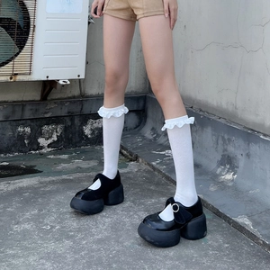 Detailed view of white ruffled Lolita calf socks paired with black platform Mary Jane shoes