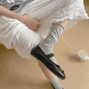 Detail of grey ribbed ballet socks with bow accent worn with black flat shoes