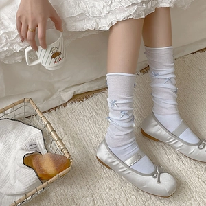 Close-up of white mesh knee high socks with blue bows and silver satin Mary Jane shoes