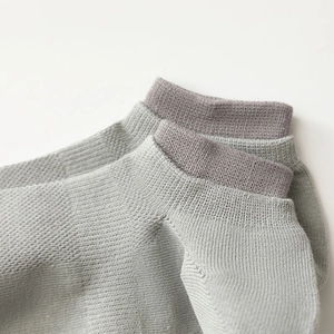 Detailed close-up of breathable mesh knit texture and ribbed cuff on light grey cotton socks