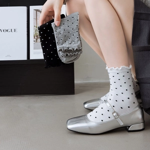 Close-up of frilly edge polka dot socks styled with silver Mary Jane shoes