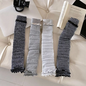 Close-up of ballet-style knitted leg warmers with ribbons in grey and white tones