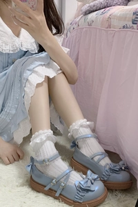 Détail de chaussures Mary Jane bleu clair avec chaussettes blanches et boucle coeur