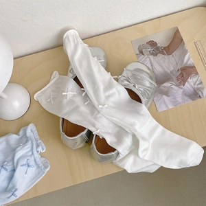 Detail view of light blue and white ballet style socks with delicate ribbon bows