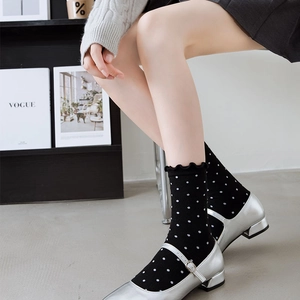 Close-up of black mid-calf socks with white polka dots and elegant ruffled cuffs