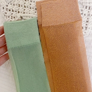 Detailed texture of shiny lurex calf socks in light green and golden orange knits