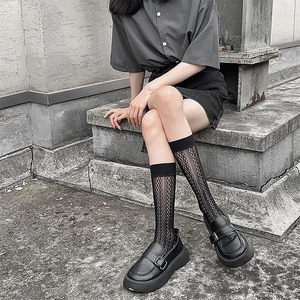 Detail of black lace hollow knee-high socks paired with platform square-toe leather shoes