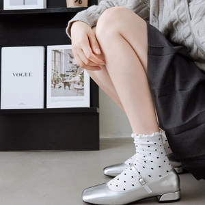 Detail of silver Mary Jane shoes paired with white polka dot ruffle socks and bow accents