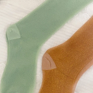 Macro detail of mint green and mustard yellow knit socks on lace background