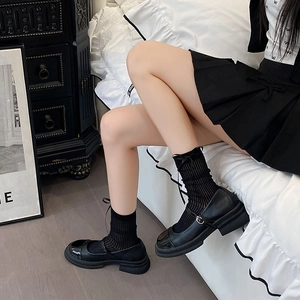 Detail of black vertical striped mid-calf socks with ribbons and Mary Jane platform shoes