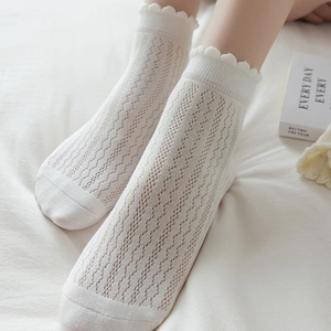 Detail of white mesh lace socks with wavy cuffs and breathable hollow knit texture