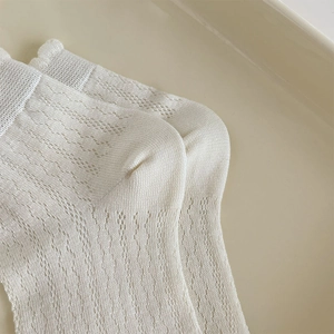 Detail of white breathable mesh lace socks with vertical knit pattern and soft texture