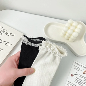Detailed view of lace trim and pearl embellishments on knit cotton socks for women