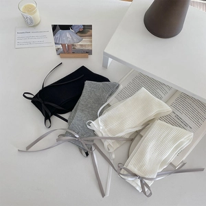 Flat lay of ballet-style ribbon bow socks in black, white, and grey colors