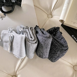 Detail of four pairs of grey knit leg warmers with bows and silver lurex accents