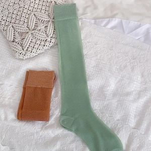 Detail of light green and orange brown ribbed knit stockings on white lace bedding