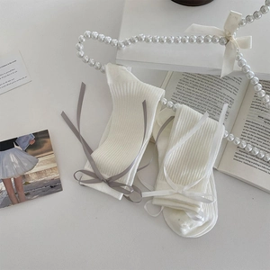 Detail of white ribbed crew socks with chic grey and white bow accents for a ballet style
