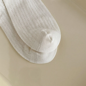 Close-up of white lace knit socks with hollow mesh texture for breathability