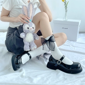 Détail de chaussettes Lolita blanches avec grands nœuds en mesh noir et chaussures Mary Jane