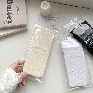 Detail of hollow lace mesh texture on calf-high cotton socks in three classic colors