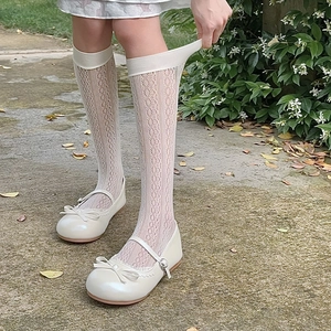 Close-up of white Mary Jane shoes with bow detail and lace hollow mesh calf socks