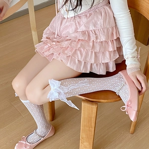 Détail de chaussettes hautes en dentelle blanche avec nœud et perle sur un mannequin