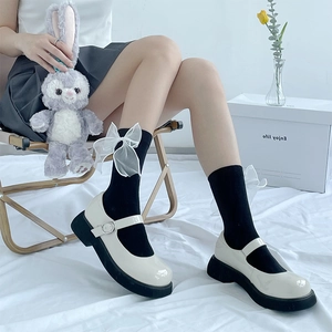 Détail du nœud en organza blanc sur chaussettes hautes et chaussures Mary Jane noires