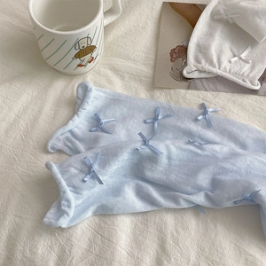 Detail of balletcore knit socks featuring delicate ribbon bows on textured mesh fabric