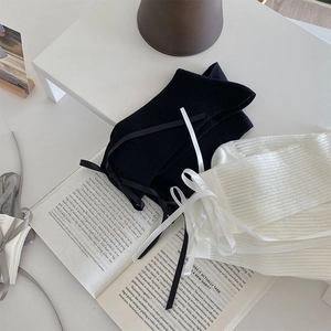Detailed view of ribbed knit socks with elegant ribbon bows on a vintage book background