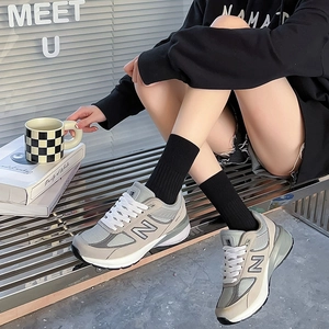 Close-up of grey leather sneakers paired with vertical striped black mid-calf socks