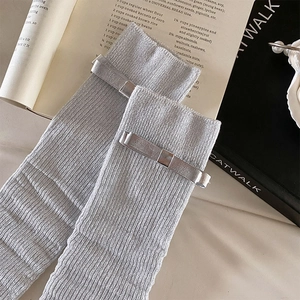Detailed texture of silver ribbed leg warmers with metallic bows on vintage background
