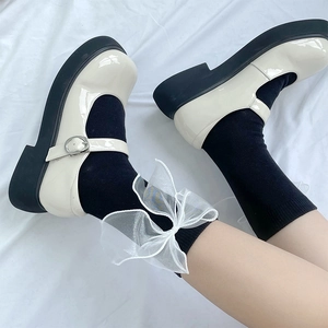 Détail du nœud en organza blanc avec des chaussures Mary Jane à plateforme en vernis crème