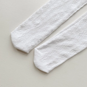 Close-up of white hollow lace pattern on breathable knee-high socks for girls