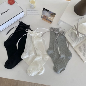 Detail of knit crew socks with satin ribbons and vertical ribbing in black white and grey