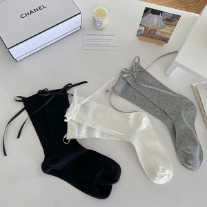Detailed close-up of ribbed knit socks with silk ribbons in black, white and grey
