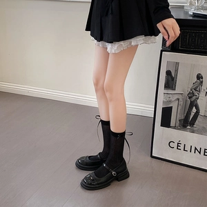 Detail of black mid-calf socks with ribbon bows paired with Mary Jane shoes